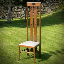 Load image into Gallery viewer, Wooden chair with a white cushion on a grassy area with a stone wall in the background