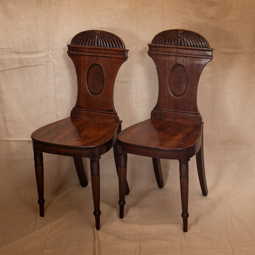 Pair of wooden chairs with intricate back designs on a beige background