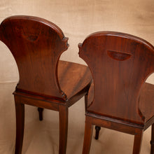 Load image into Gallery viewer, Two wooden chairs with intricate back designs on a beige background
